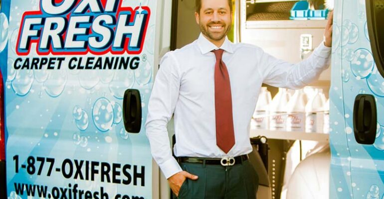 Jonathan Barnett, President and CEO of Oxi Fresh, standing in front of the carpet cleaning van