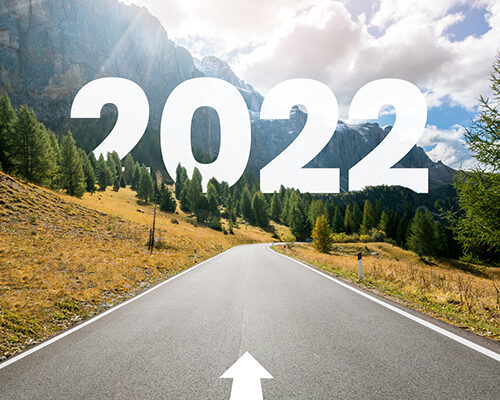 Road with an arrow pointing forward. The road runs into the mountains. The word "2022" in blocky white text floats in the background.
