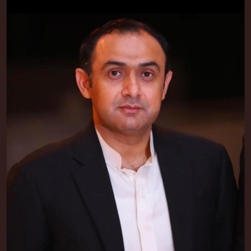 Oxi Fresh Carpet Cleaning franchisee Malik Khar poses in a dark suit against a dark background.